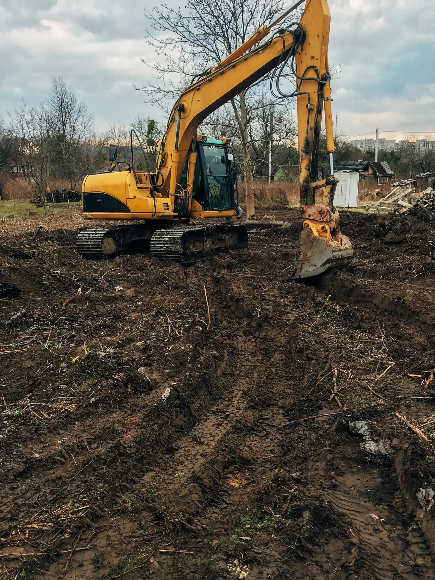 Bulldozer clearing land by removing old trees, roots, and branches to prepare the site for construction.