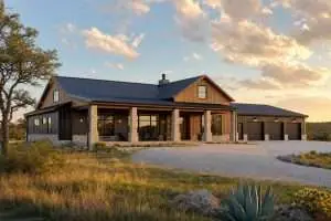 Modern black metal barndominium with cedar accents and attached shop on Central Texas ranch land at sunset